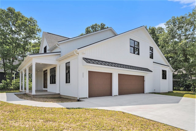 view of side of home with a porch, a garage, and a lawn