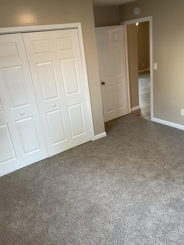 unfurnished bedroom with dark carpet and a closet