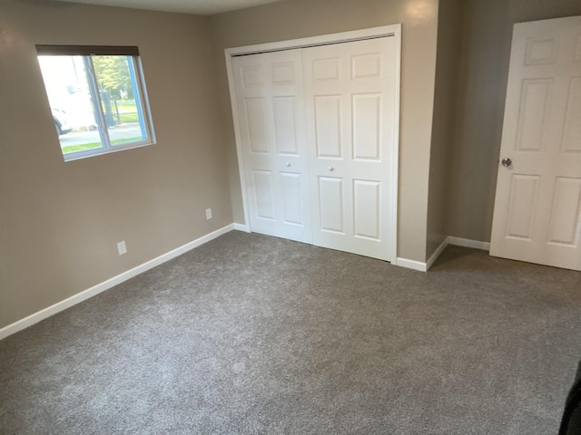 unfurnished bedroom with dark carpet and a closet