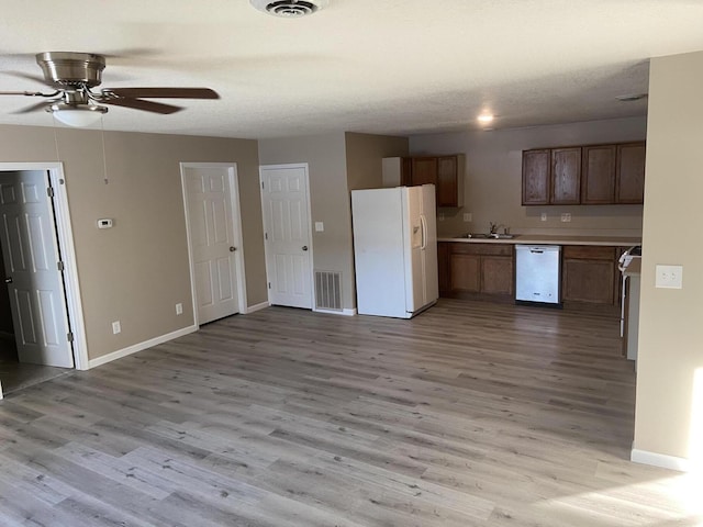 kitchen with sink, white appliances, ceiling fan, a textured ceiling, and light wood-type flooring