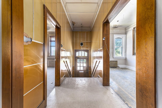 hallway featuring ornamental molding, radiator, and concrete floors