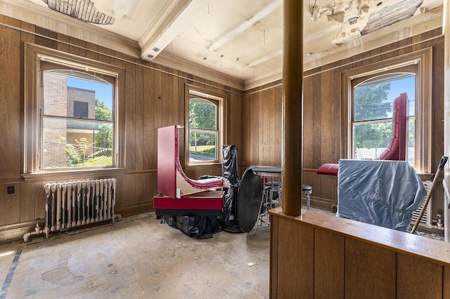 miscellaneous room with radiator heating unit, beam ceiling, and wood walls