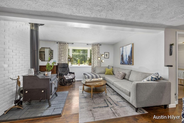 living room with dark wood-type flooring, a textured ceiling, and a wood stove