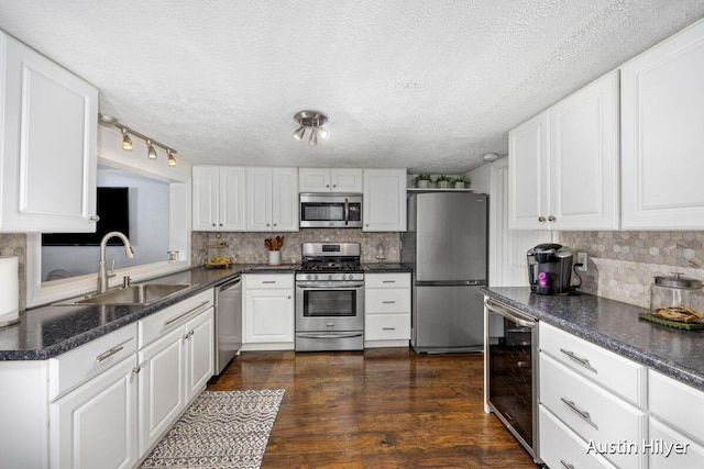 kitchen with wine cooler, sink, white cabinetry, dark hardwood / wood-style flooring, and stainless steel appliances