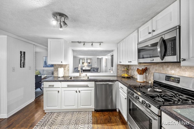 kitchen with dark hardwood / wood-style floors, white cabinetry, sink, backsplash, and stainless steel appliances