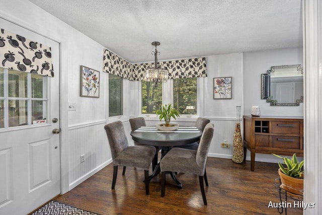 dining space featuring a notable chandelier, dark wood-type flooring, and a textured ceiling