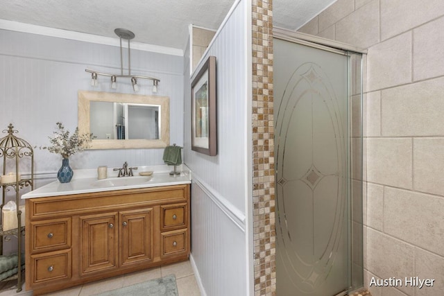 bathroom featuring vanity, ornamental molding, a textured ceiling, tile patterned floors, and walk in shower