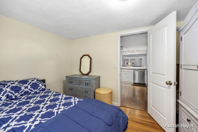 bedroom featuring wood-type flooring, a textured ceiling, and ensuite bath