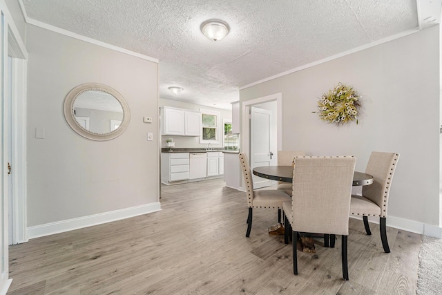 dining room with ornamental molding, sink, a textured ceiling, and light wood-type flooring