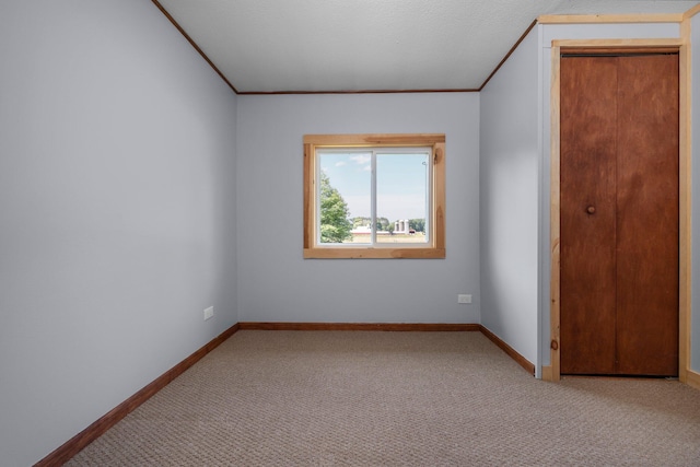 empty room featuring crown molding and light carpet