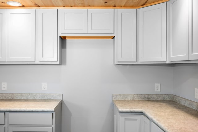 kitchen featuring wooden ceiling and white cabinets