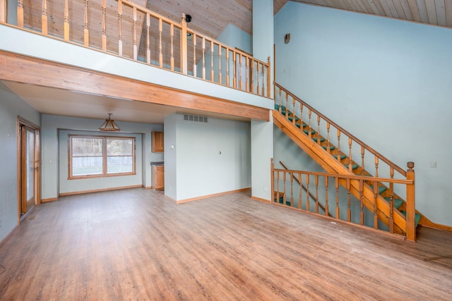 unfurnished living room featuring wood-type flooring and high vaulted ceiling