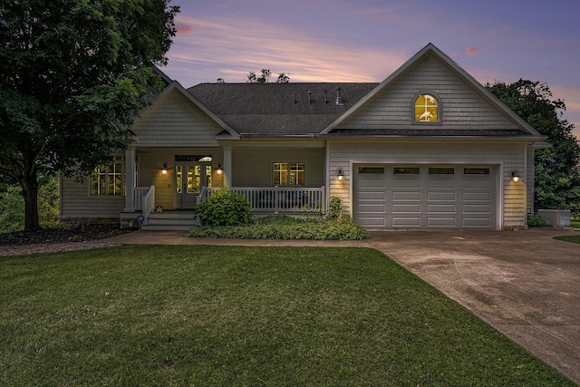 view of front of property with a garage, covered porch, and a lawn