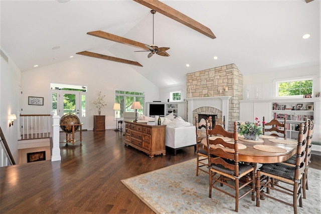 dining space featuring a stone fireplace, dark hardwood / wood-style floors, high vaulted ceiling, beamed ceiling, and ceiling fan