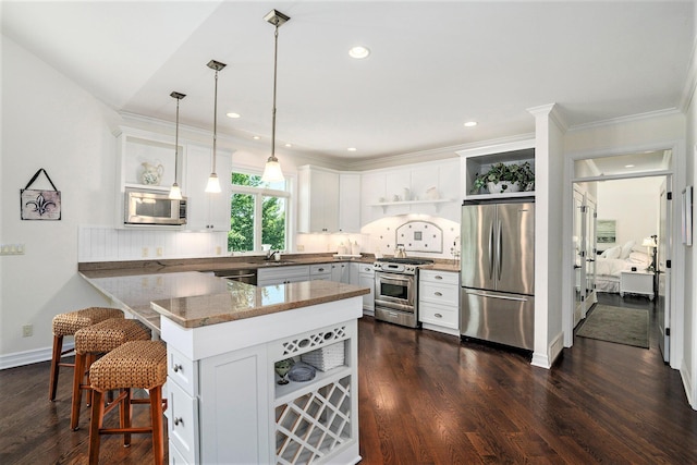 kitchen with appliances with stainless steel finishes, pendant lighting, white cabinetry, a breakfast bar area, and kitchen peninsula