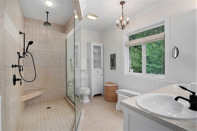 bathroom featuring tiled shower, toilet, ornamental molding, vanity, and a notable chandelier