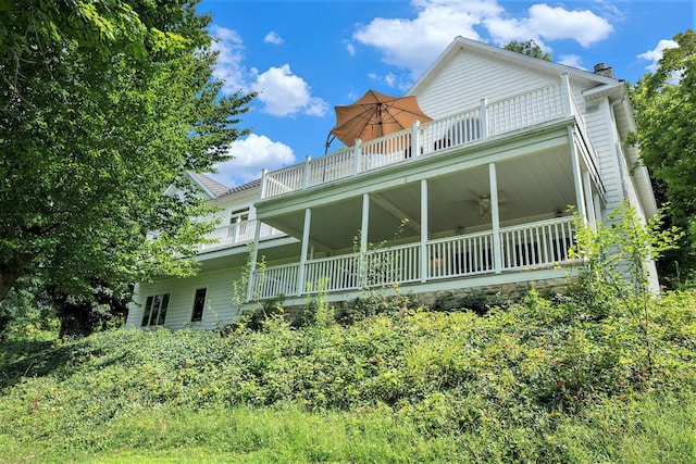 rear view of property with a balcony and ceiling fan