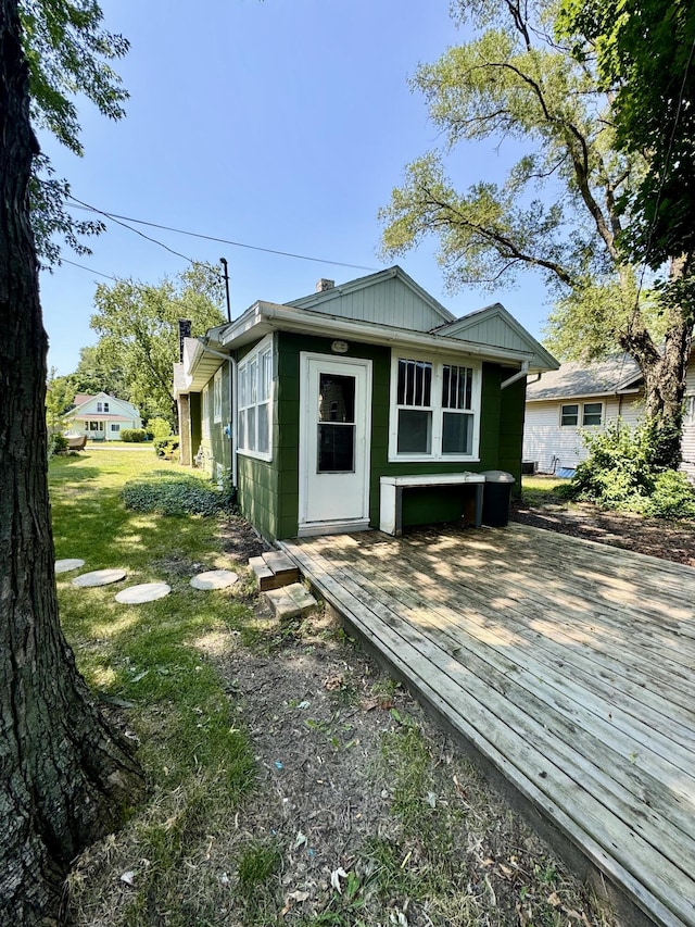 rear view of property with a wooden deck and a lawn