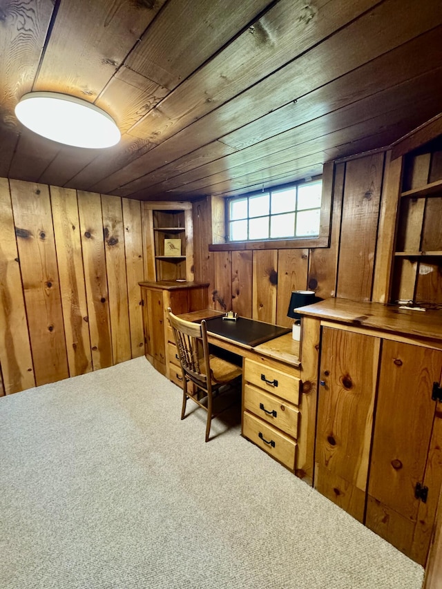 carpeted office with wood ceiling, wooden walls, and built in desk