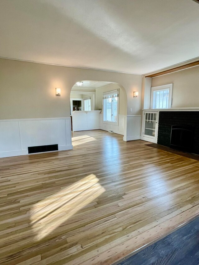 unfurnished living room with ornamental molding and light hardwood / wood-style floors