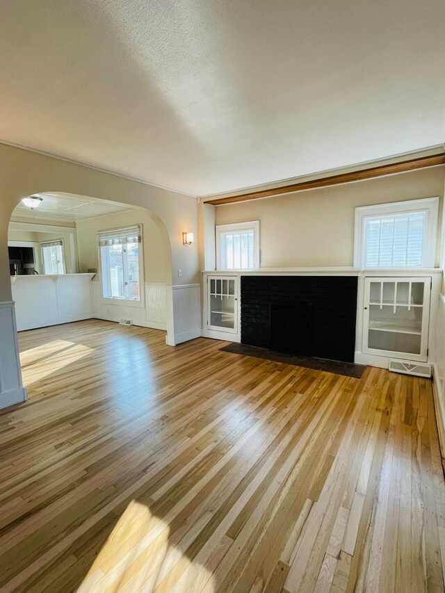 unfurnished living room featuring plenty of natural light, a textured ceiling, and light hardwood / wood-style floors