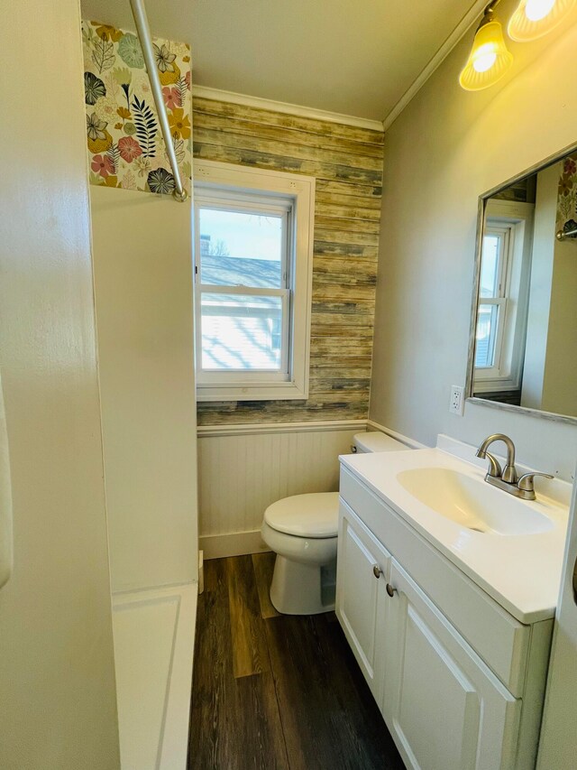 bathroom featuring toilet, wood walls, crown molding, wood-type flooring, and vanity