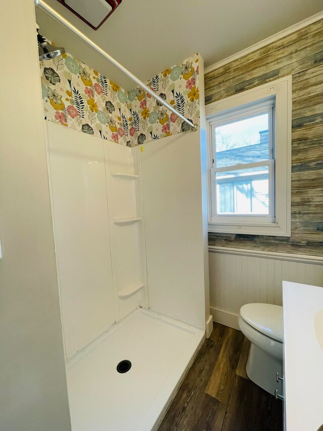 bathroom with hardwood / wood-style flooring, wooden walls, toilet, and walk in shower