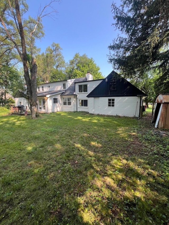 back of house featuring a lawn and a storage unit