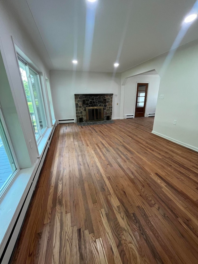 unfurnished living room with a baseboard radiator, dark hardwood / wood-style flooring, and a fireplace