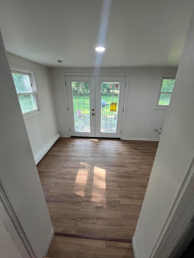 empty room with french doors, a baseboard heating unit, and wood-type flooring