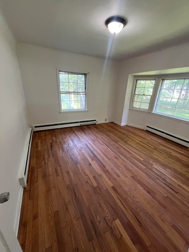 empty room featuring baseboard heating and hardwood / wood-style floors