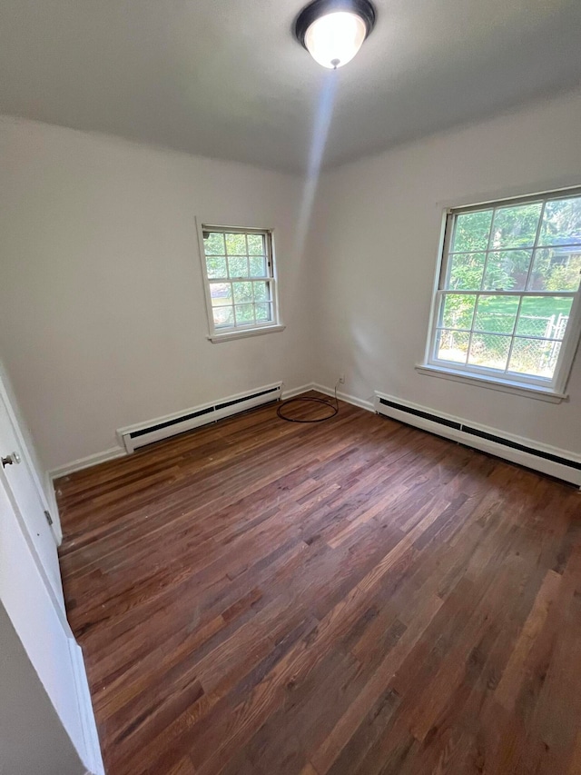 empty room featuring hardwood / wood-style floors, a baseboard radiator, and a wealth of natural light