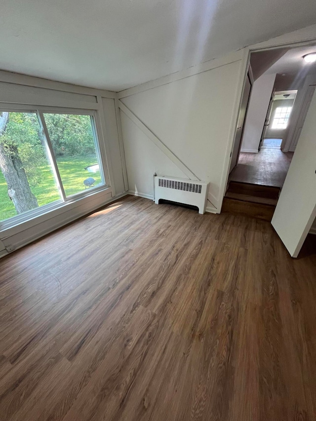 additional living space with hardwood / wood-style flooring and radiator heating unit