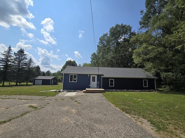 single story home with an outbuilding, a garage, and a front lawn