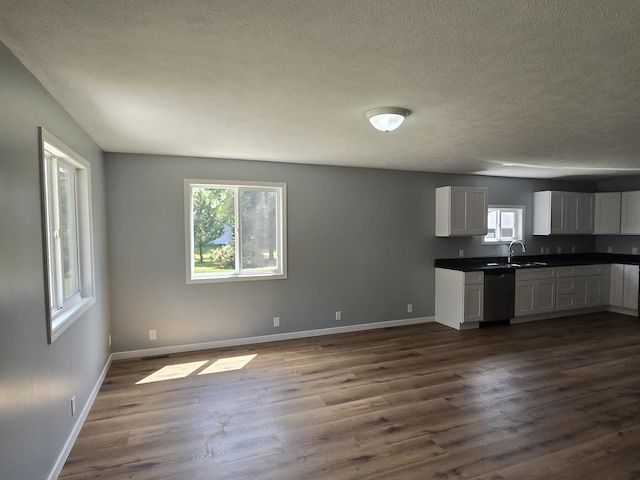 kitchen featuring dishwasher, sink, white cabinets, dark hardwood / wood-style flooring, and a textured ceiling