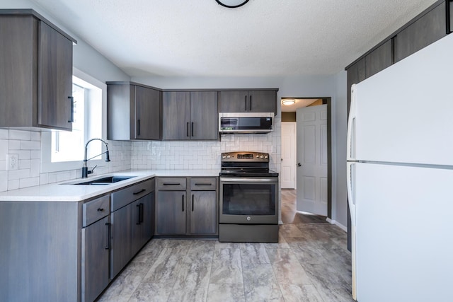 kitchen with decorative backsplash, stainless steel appliances, sink, and a textured ceiling