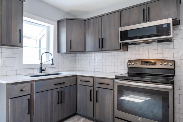 kitchen with stainless steel appliances, sink, dark brown cabinets, and backsplash