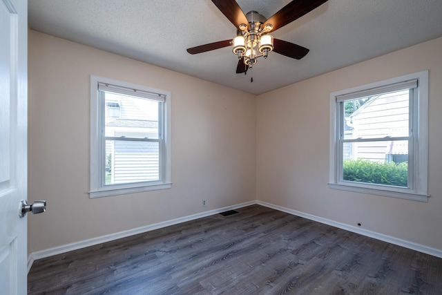 unfurnished room with ceiling fan, dark hardwood / wood-style floors, a wealth of natural light, and a textured ceiling