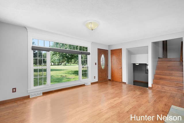 unfurnished living room with light hardwood / wood-style floors and a textured ceiling