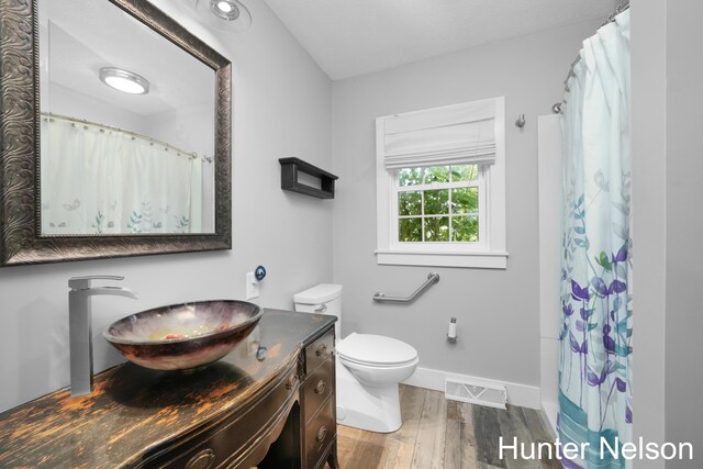 bathroom with a shower with curtain, vanity, hardwood / wood-style floors, and toilet