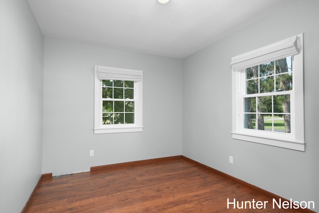 spare room with a healthy amount of sunlight and dark hardwood / wood-style flooring