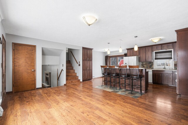 kitchen with a kitchen bar, white fridge with ice dispenser, a kitchen island, dark hardwood / wood-style floors, and decorative light fixtures