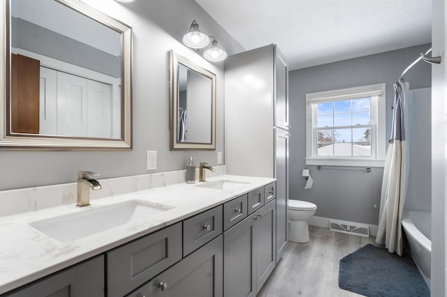 full bathroom with vanity, a textured ceiling, shower / tub combo, toilet, and hardwood / wood-style flooring