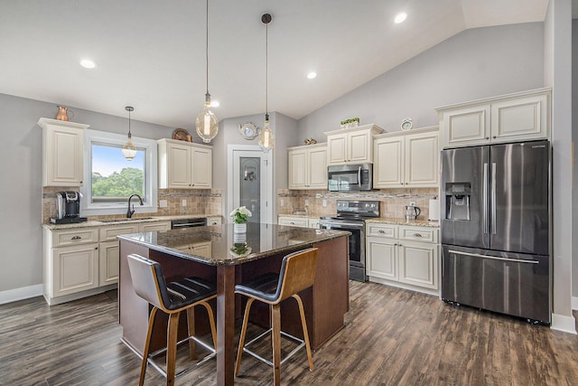 kitchen featuring dark wood finished floors, a sink, stainless steel appliances, vaulted ceiling, and a center island