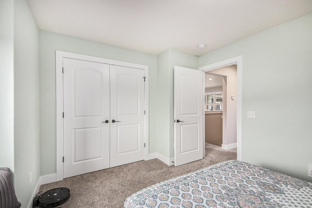 bedroom with light carpet, a closet, and baseboards