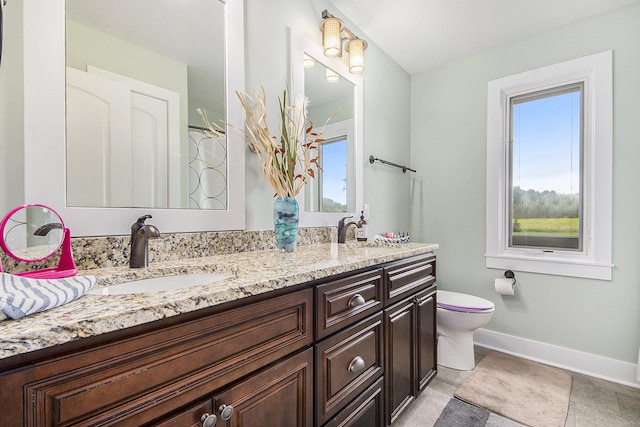 full bath featuring double vanity, toilet, baseboards, and a sink