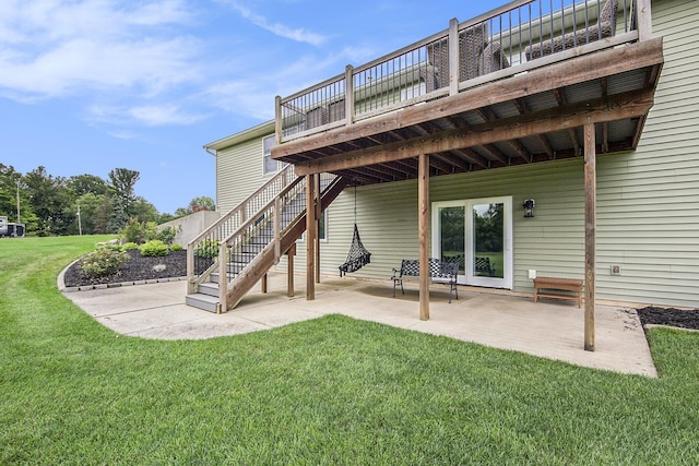 back of house featuring a wooden deck, a lawn, stairs, and a patio area