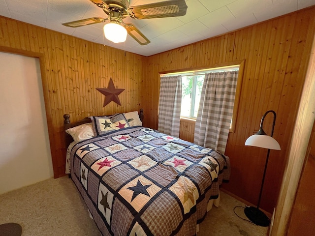 carpeted bedroom with ceiling fan and wood walls