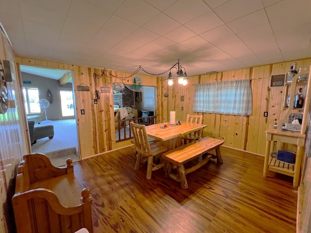 dining room with lofted ceiling, hardwood / wood-style floors, and wood walls