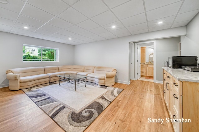 living room featuring a drop ceiling and light hardwood / wood-style flooring